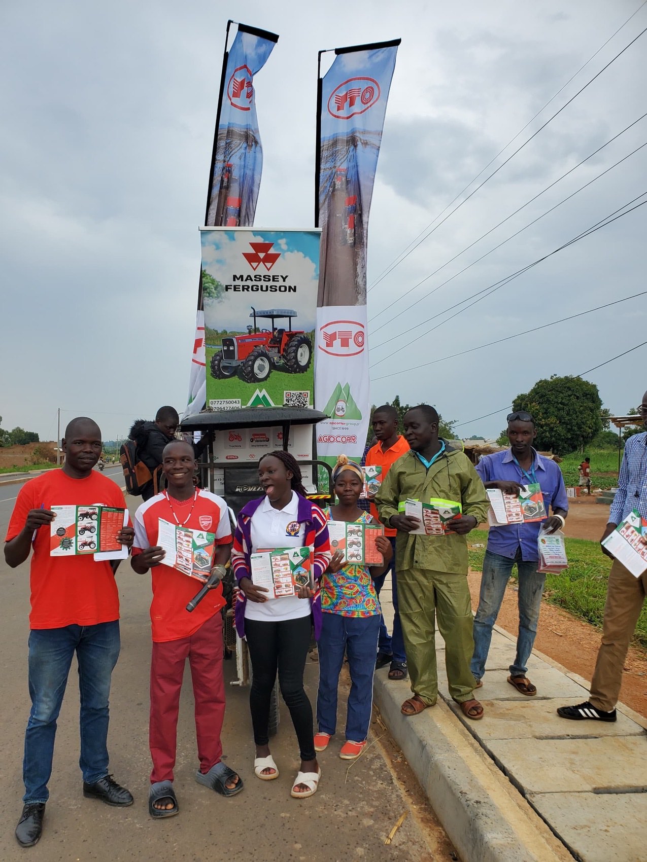 Agrocorner's roadside promotion with YTO and Massey Ferguson banners, people holding equipment flyers